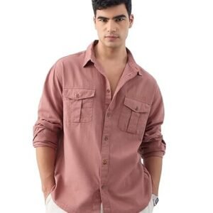 A man with dark hair wearing a mauve-colored, long-sleeved utility shirt with two chest pockets, paired with white trousers against a plain white background.