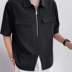 Man wearing a black short-sleeve half-zip shirt with chest pockets paired with white pants.