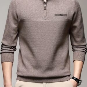 A man wearing a slim-fit, taupe brown quarter-zip sweater with horizontal chest detailing and ribbed cuffs, paired with beige trousers.
