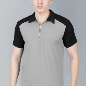 Front-facing view of a man wearing a grey and black color-block polo t-shirt with a metallic quarter-zip neck, black raglan-style sleeves, and a grey torso, paired with dark washed jeans and a watch.