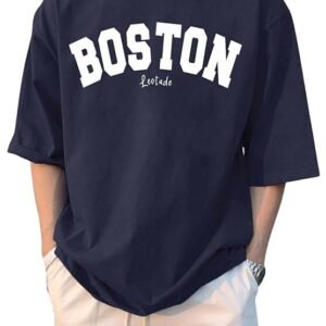 A man wearing an oversized navy blue t-shirt with "BOSTON" printed in bold white arched letters across the chest, paired with off-white drawstring shorts.