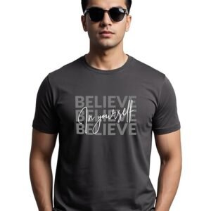 A man wearing a charcoal grey crew-neck t-shirt with a graphic design featuring the word "BELIEVE" repeated in a grid and "in yourself" written in white cursive script across the center.